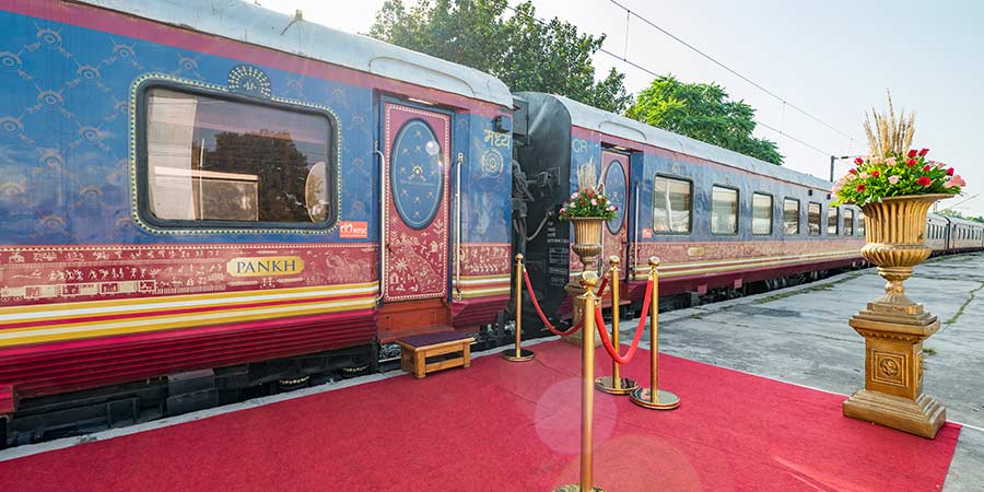 A red carpet leads up to the beautiful Deccan Odyssey train cart. 